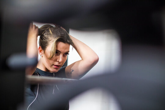 Attractive woman ties her hair up during a workout at the gym.
