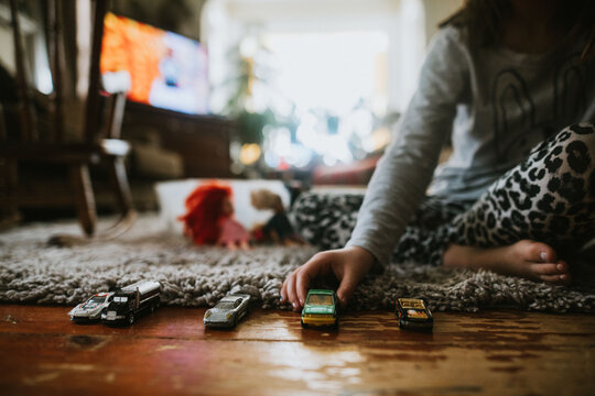 child's hand playing with toy cars on floor