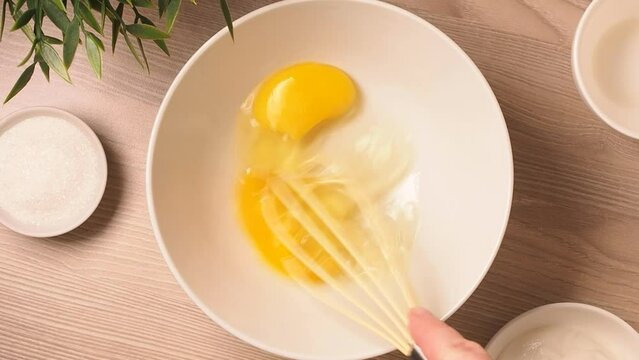 Beat eggs with sugar with a hand whisk in a bowl. The process of making dessert.