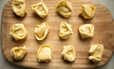 uncooked ravioli on a wooden cutting board close up top view. raw dumplings on a wooden board