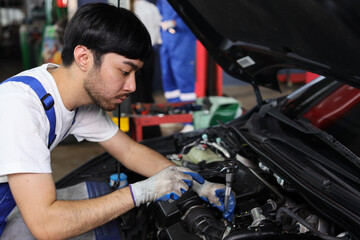 Fototapeta na wymiar Man technician car mechanic in half uniform checking maintenance a car service at repair garage station. Worker holding wrench and fixing breakdown vehicle. Concept of car center repair service.