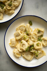 ready hot ravioli with pesto sauce and grated cheese on a white plate close-up. dumplings ready to eat	