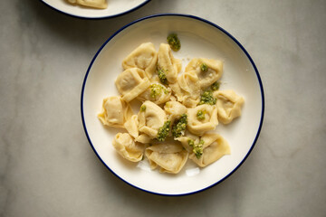 ready hot ravioli with pesto sauce and grated cheese on a white plate close-up. dumplings ready to eat	