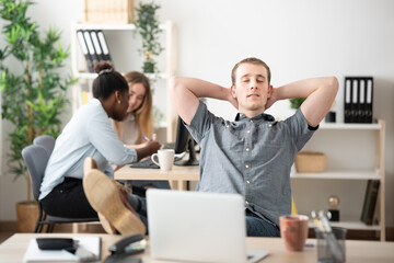 Lazy office worker relaxing hands behind head in the office