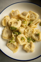 ready hot ravioli with pesto sauce and grated cheese on a white plate close-up. dumplings ready to eat