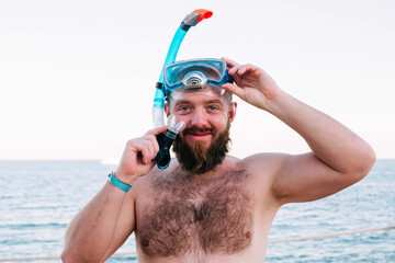 Bearded man in diving mask on a tropical island. Male tourist having fun diving on sea background....