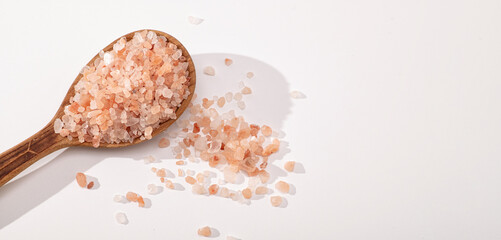 Fototapeta na wymiar Pink Himalayan salt in a wooden spoon on a white background, banner, place for text
