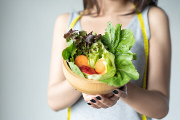 Eat high fiber and low calories foods for good health.Young woman eating bowl of fresh salad and pure water in the morning.