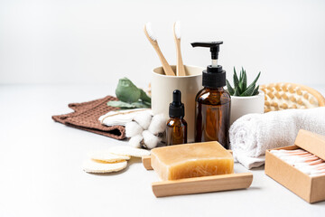 Natural bathroom and home spa tools. Zero waste sustainable lifestyle concept. Bamboo toothbrush, natural soap bar, cotton pads, homemade DIY beauty products in reusable bottles on white background.
