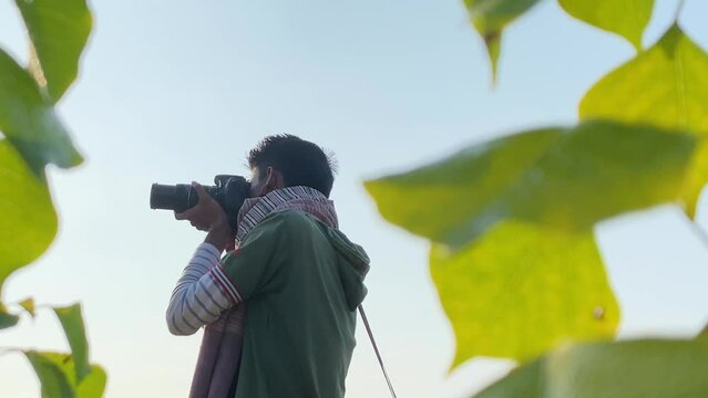 Portrait of South Asian young man taking photos of nature, leaf in front of lens
