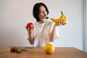 朝食のフルーツを手に取って悩む女性