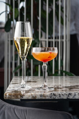 Champagne coupe glass of refreshing orange cocktail on gray table surface