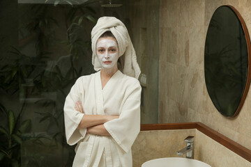 Portrait of a woman with beauty face mask in the bathroom, skin care and pampering time concept at...