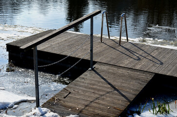 Obraz premium frozen river has modified entrances to water from embankment. swimmer decides to take a bath as part of conditioning and hardening after sauna, it is possible to use stainless steel steps, ladder