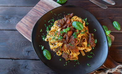Pasta with Beef meat on a plate isolated on dark wooden background with copy space
