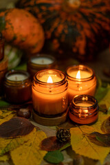 Soy candles burn in glass jars. Tree leaves, pumpkin. Comfort at home. Candle in a brown jar. Scent and light. Scented handmade candle. Aroma therapy. Autumn mood. Cozy home decor in fall.