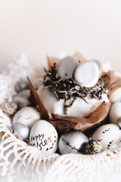 Painted silver and white Easter eggs on a light background and cake, postcard, free space for text, selective focus