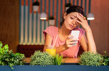 Unhappy thoughtful woman looking at smartphone screen, reading message with bad news.