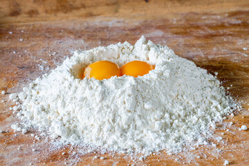Flour and two egg yolks on wooden board