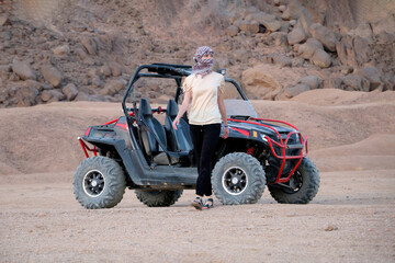 Young woman was riding a buggy. Walks away from him in the desert and looks away.
