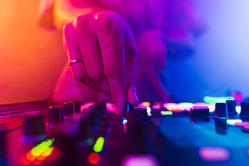 Close up of DJ hands on dj console mixer during concert in the club