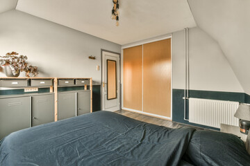 a bedroom with a bed, desk and cupboards on the wall next to an open door that leads to another room