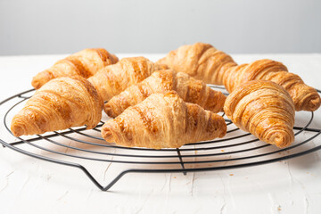Close-up of small croissants on rack on white table, horizontal, with copy space