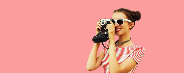 Portrait of happy young woman photographer with film camera, female with cool girly hairstyle on pink background - obrazy, fototapety, plakaty