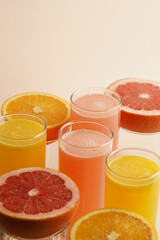 Glasses of citrus juice with sliced fruits on pastel background