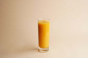 Glass of orange juice on pastel color background