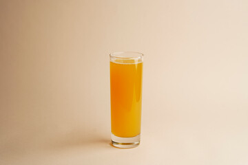 Glass of orange juice on pastel color background