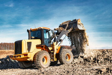 Fototapeta premium Powerful wheel loader or bulldozer working on a quarry or construction site. Earthworks in construction. Powerful modern equipment for earthworks.