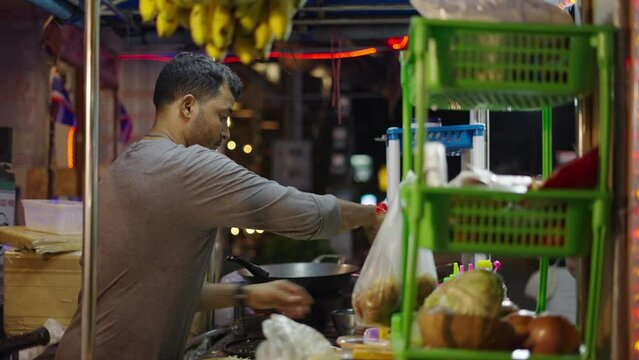 Thai street seller pouring culinary products to a traditional thai pancake