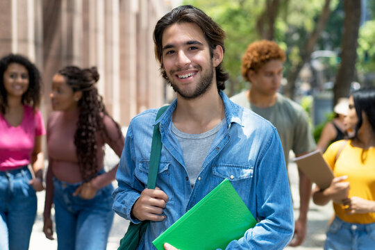 Laughing latin american male student with group of caucasian and african american young adults