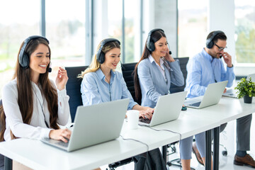 Group of friendly customer support operators working at call center.