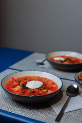 Red borscht with sour cream and horseradish on a blue tablecloth background