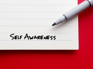On red background, pen wrote on notebook SELF AWARENESS, individual consciously knows themselves, understands character, trait and feeling knowing their own values, beliefs personal preferences