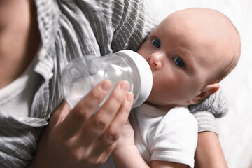 Mother feeding her little baby from bottle, closeup