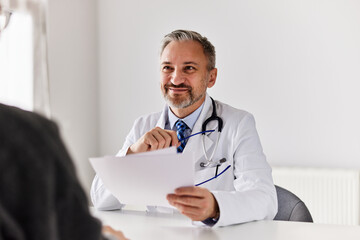 A smiling male doctor looking at his patient and holding his results.