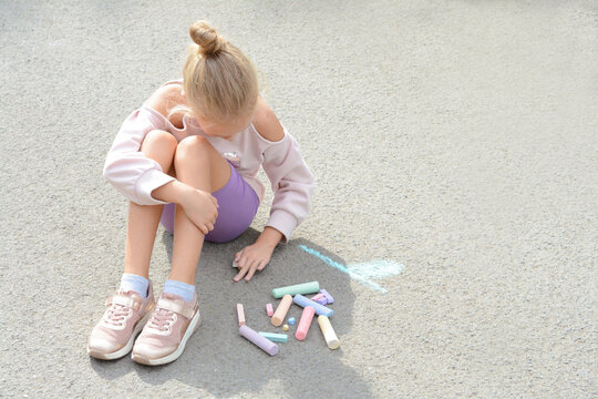 Little child drawing flower with chalk on asphalt, space for text