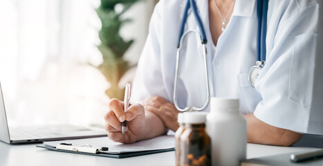 Doctor working on laptop computer and tablet and medical stethoscope on clipboard on desk, electronics medical record system EMRs concept.