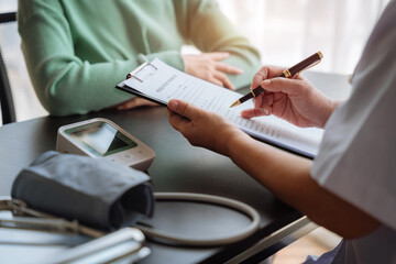 Female doctor writes prescription to patient at worktable.