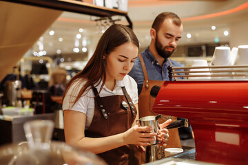 A man and a girl make coffee at a coffee machine in a coffee shop