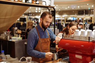 A man and a girl make coffee at a coffee machine in a coffee shop
