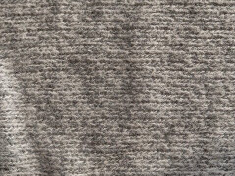 Gray knitted texture of woolen fabric close-up. Textile knit pattern wallpaper abstract background surface for design. Handmade shops matte soft cozy backdrop. Woven winter sweater clothes macro photo