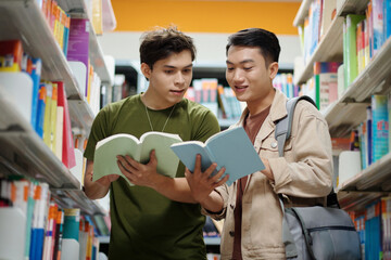 Cheerful college students discussing new books in library
