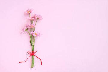 Bouquet of Pink Chrysanthemum Flowers decorated with red ribbon on pink background, Bouquet of flowers 