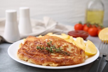 Tasty soda water battered fish, potato chips and lemon slice on light grey table