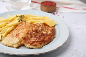 Tasty soda water battered fish, potato chips and lemon slice served on white textured table, closeup