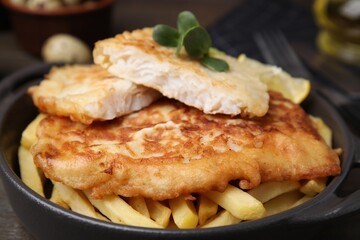 Tasty soda water battered fish and potato chips in serving pan, closeup